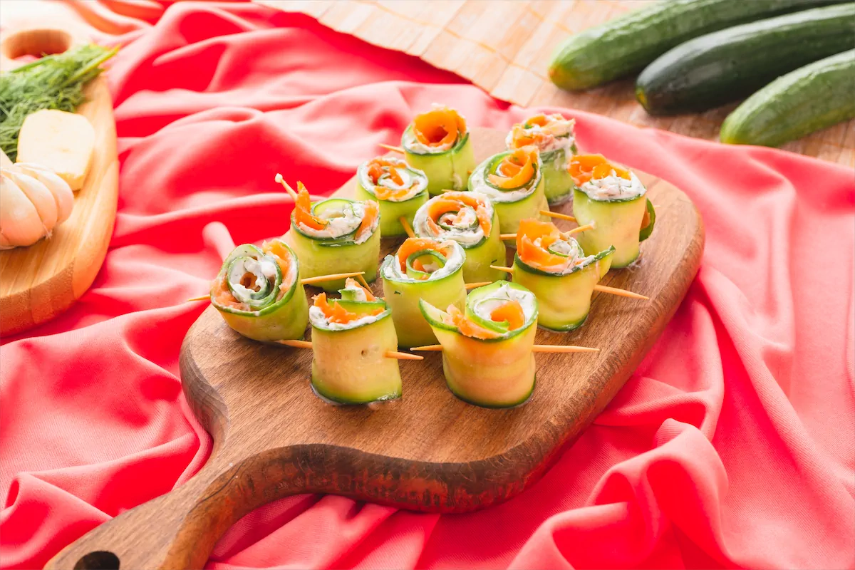 Smoked salmon cucumber rolls served on wooden serving tray.