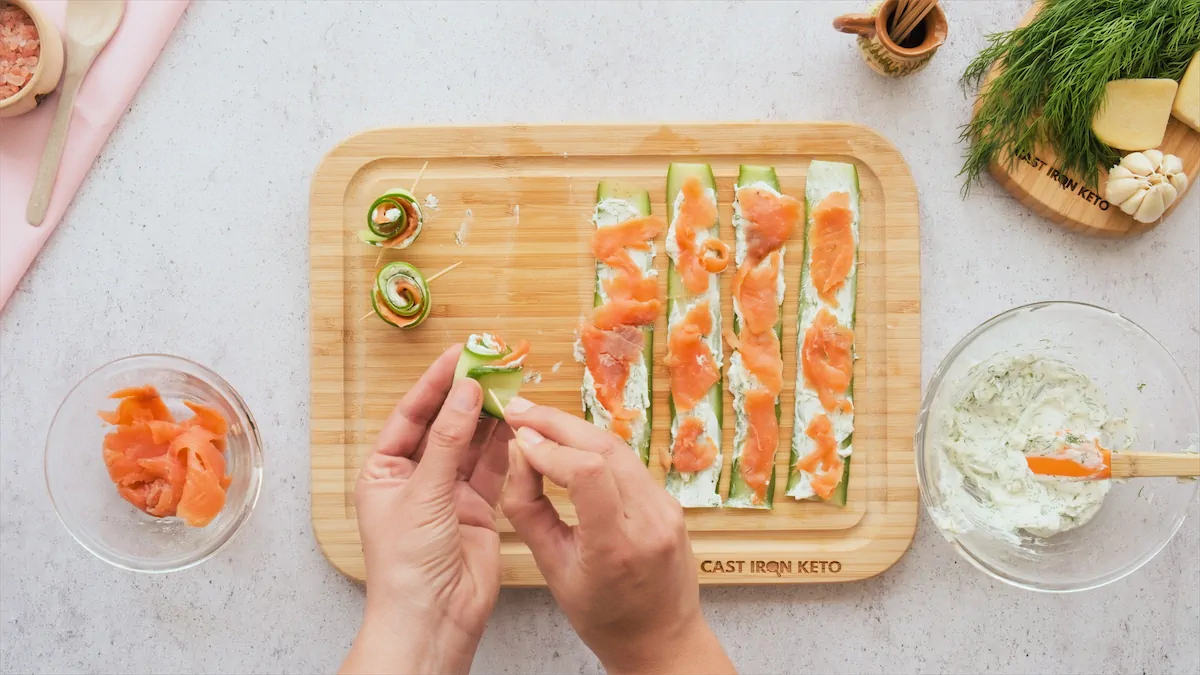 Rolling up cucumber slice containing salmon and labneh mixture and securing it by piercing with toothpick.