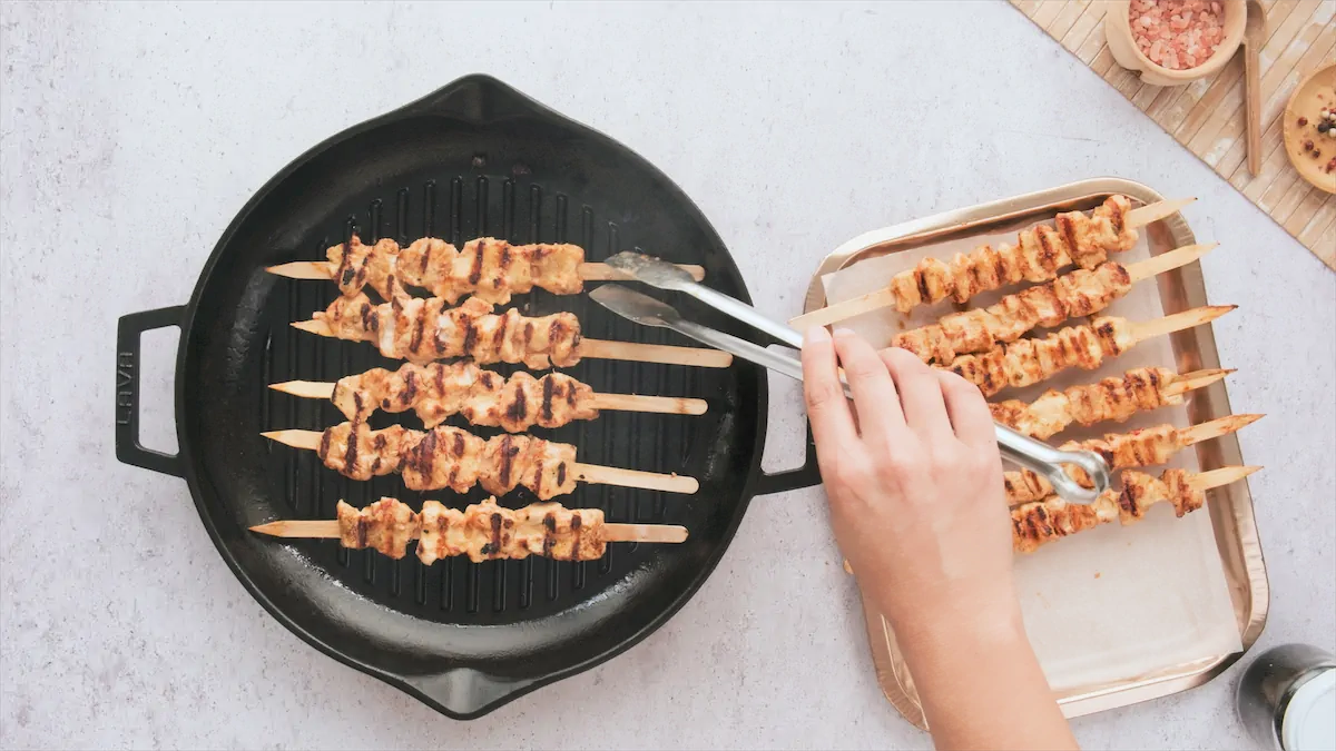 Chicken skewers grilled in a cast iron grill pan.