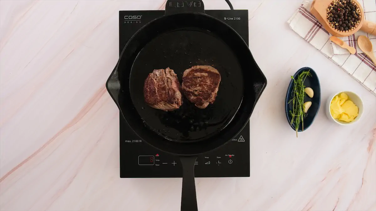 Cooking the filet mignon steaks in a pan.