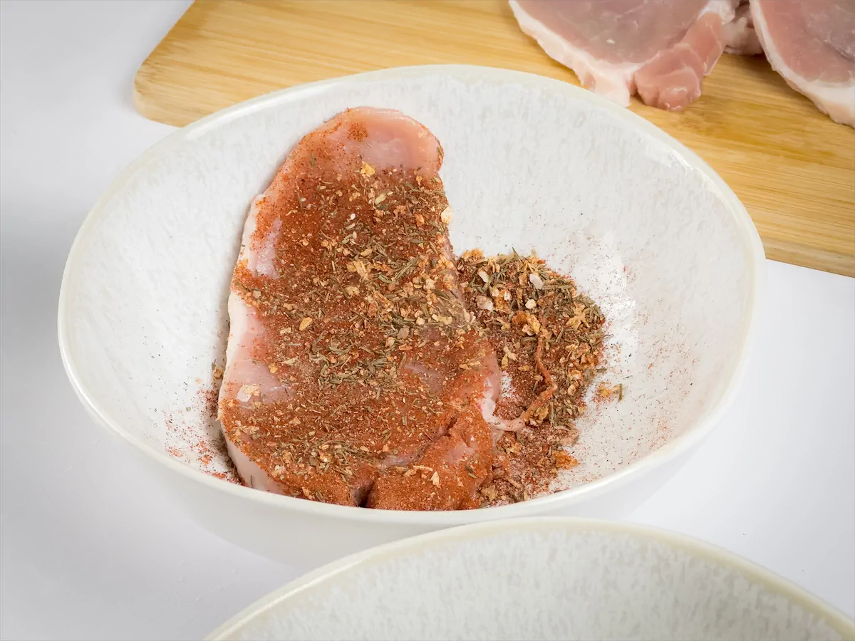 Applying spice mixture all over pork chop.