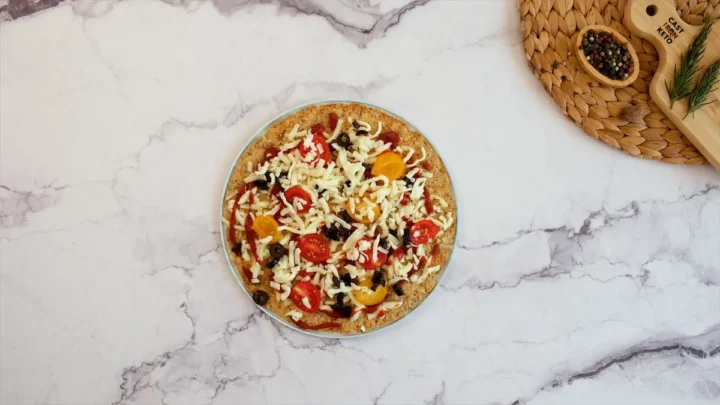 Keto chicken crust topped with cheese, tomatoes, and olives.