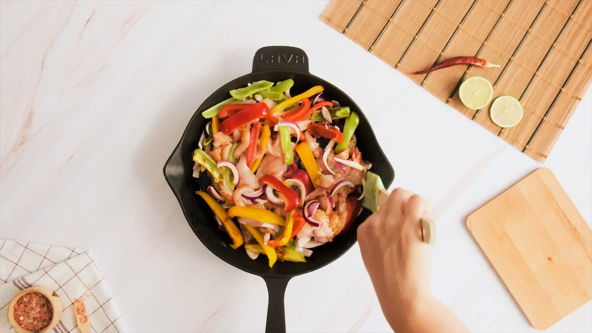 Cooking the sliced chicken and vegetables in a cast iron skillet.