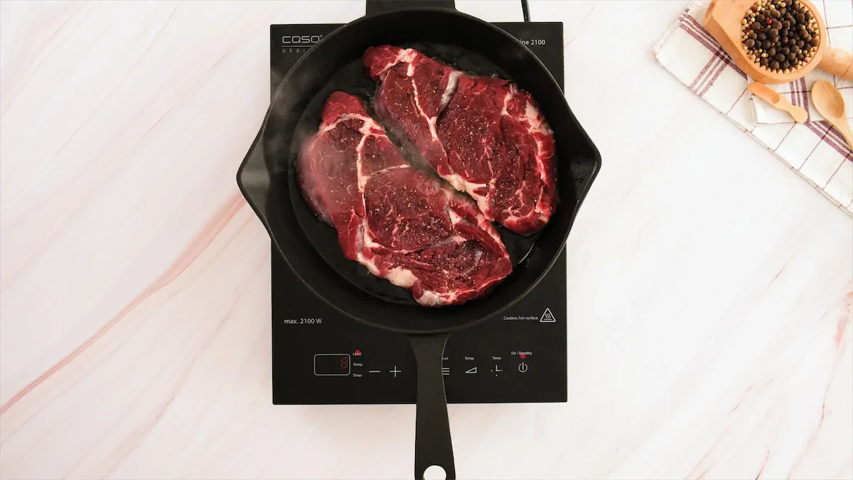 Searing steaks in a cast iron pan.