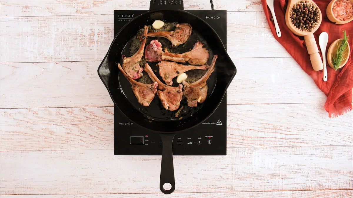 Garlic and lamb chops in a cast iron pan.