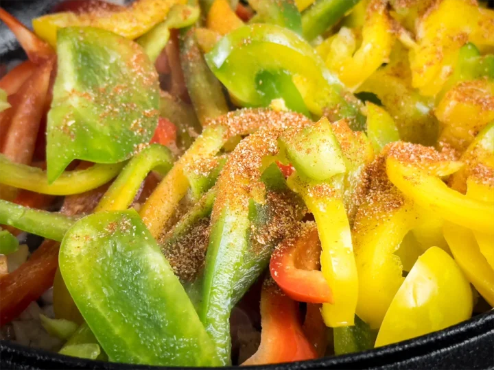 Seasoning added to bell peppers being cooked.