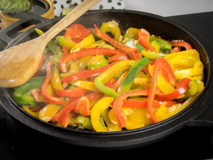 Cooking sliced bell peppers in a skillet.