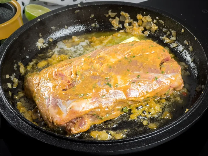 Cooking the marinated steak in a cast iron skillet.