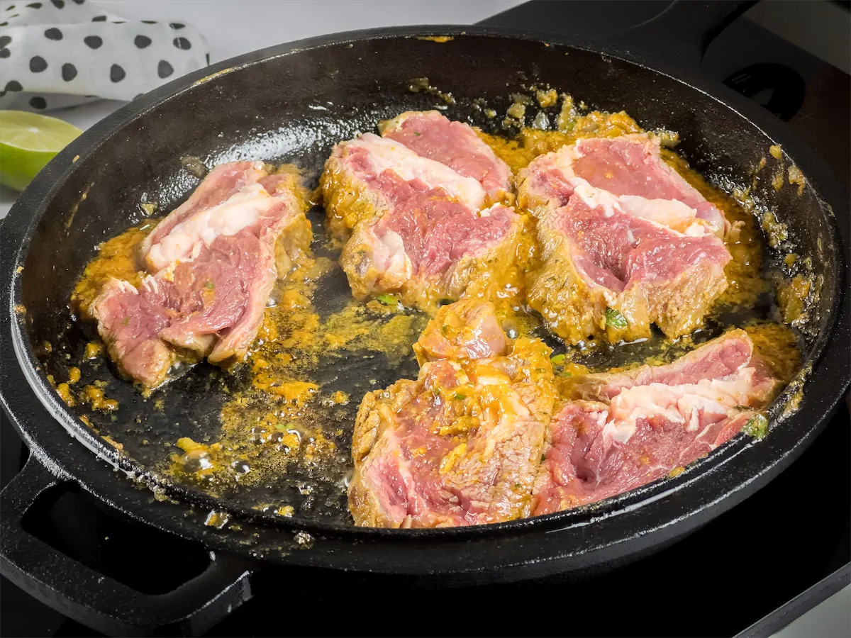 Cooking the steak slices in a skillet along with the marinade.
