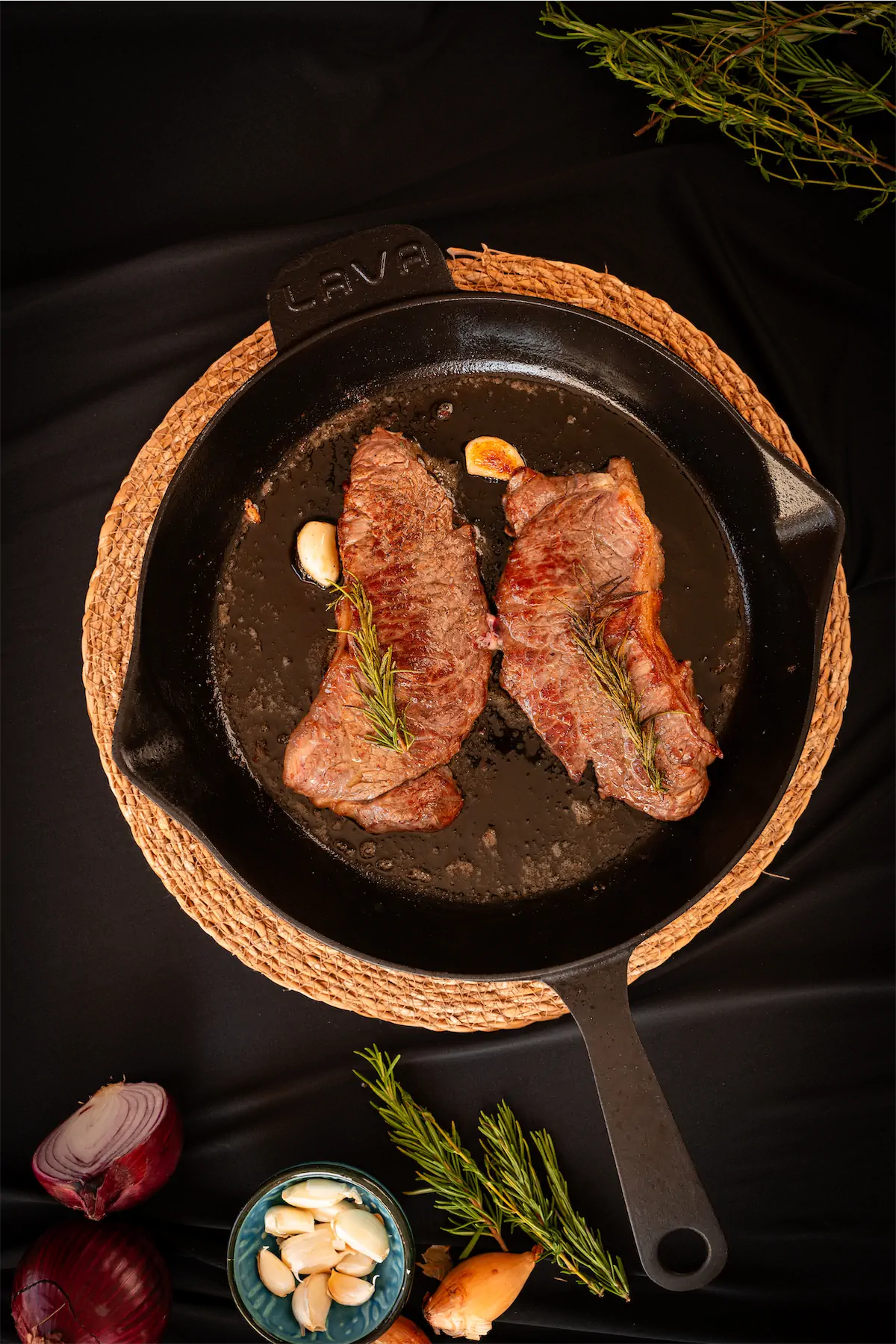 Steak on a pan seasoned with rosemary.