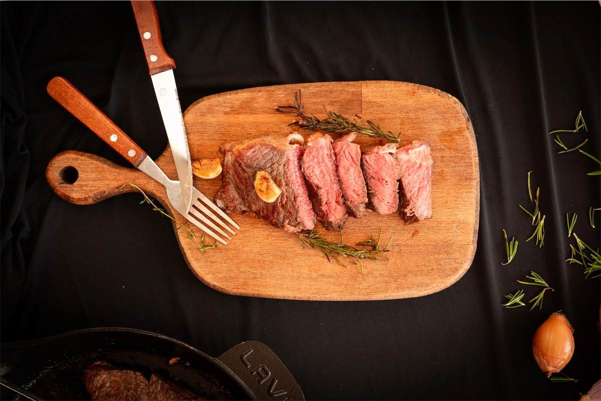 Strip steaks recipe on a wooden serving board.