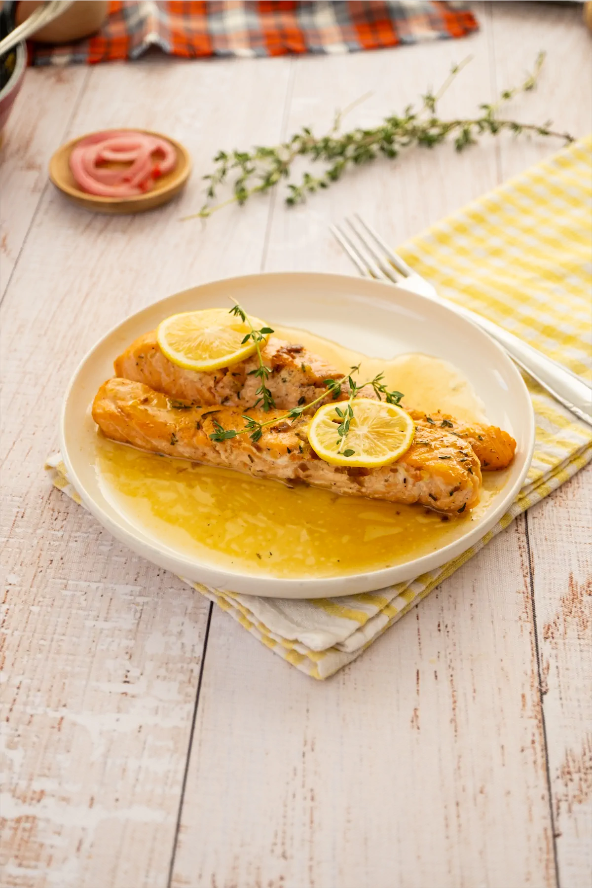 Salmon recipe with lemon slices and herbs served on a plate.