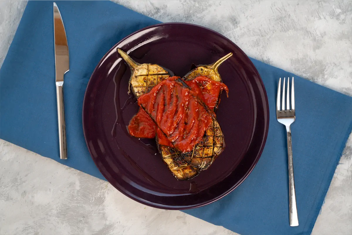 Roasted eggplant topped with tomato sauce.
