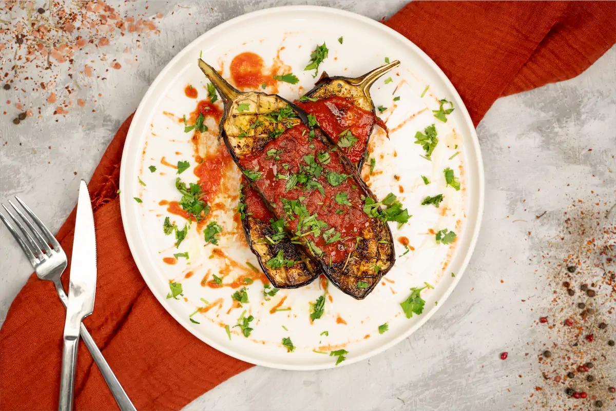 Baked eggplant recipe served on a plate with sauce.