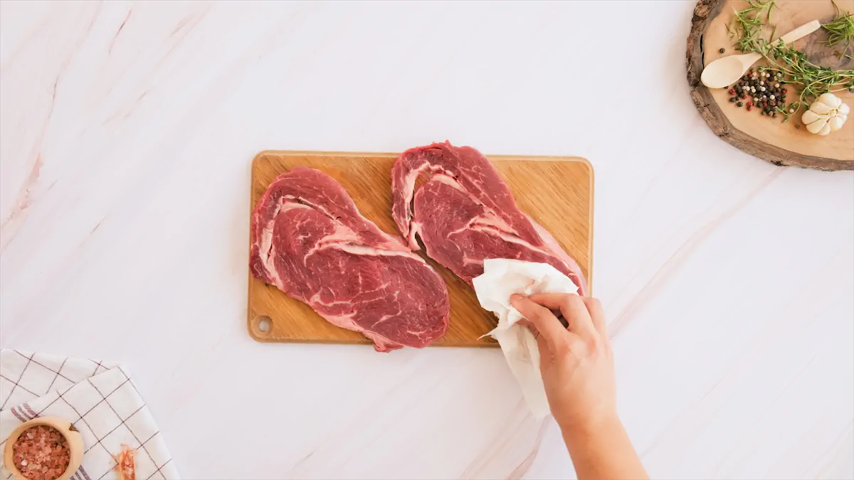 Patting the steak dry using a paper towel.