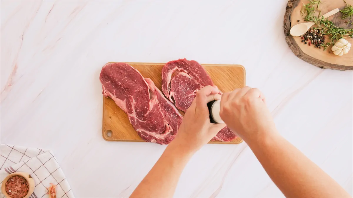 Sprinkling the steaks with salt and freshly ground black pepper.