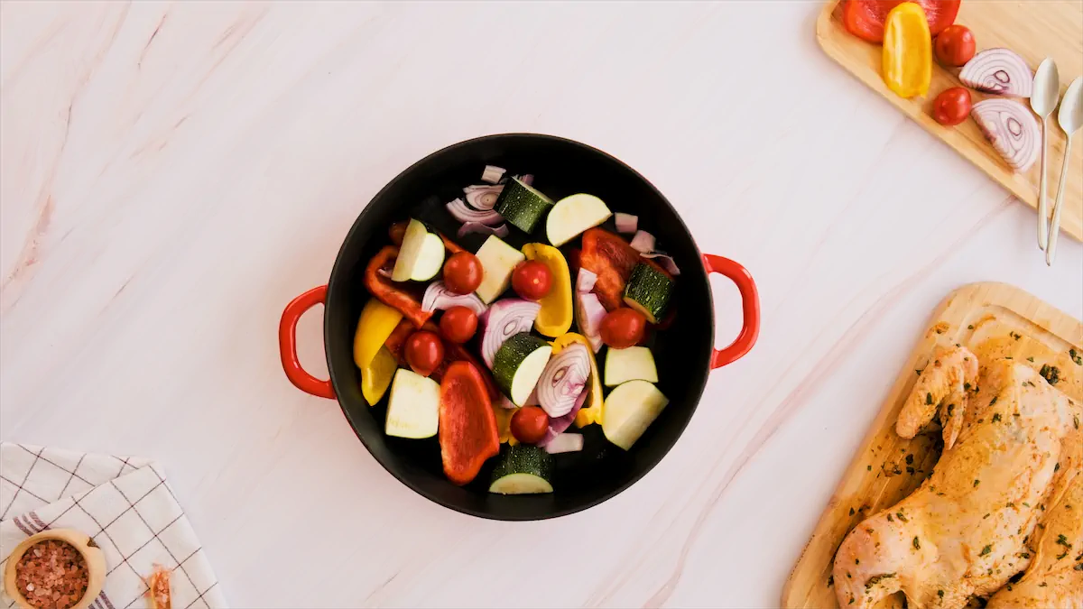 Chopped vegetables spread out in the bottom of a cast-iron pot.