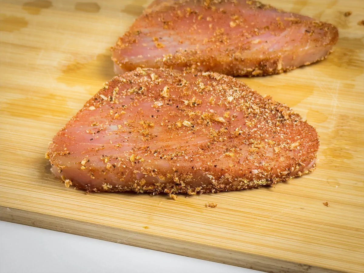 Tuna steaks coated by rubbing the prepared spice mix on both sides.