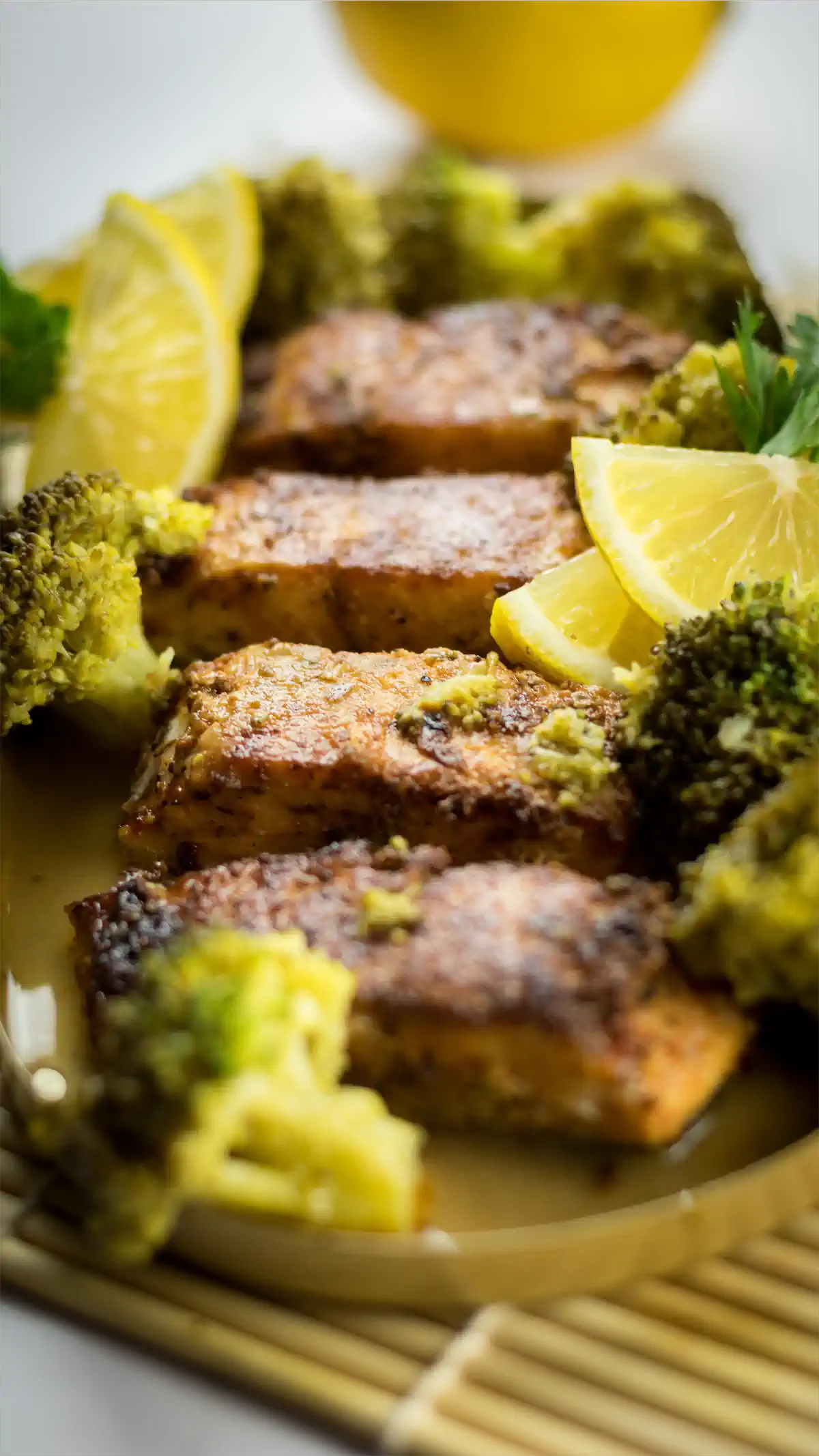 Blackened salmon in lemony butter sauce served alongside broccoli and lemon slices.