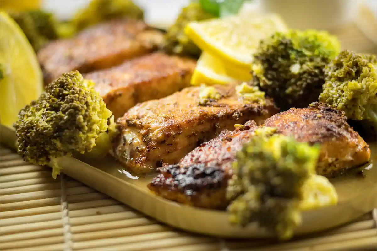 Blackened salmon in lemon butter sauce, served with broccoli on a plate.