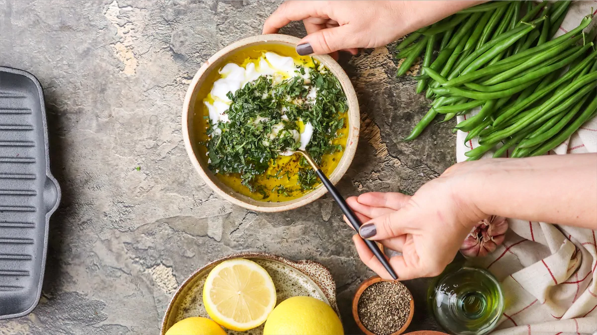 Mixing Greek yogurt, chopped mint leaves, olive oil and other ingredients to make yogurt dressing.
