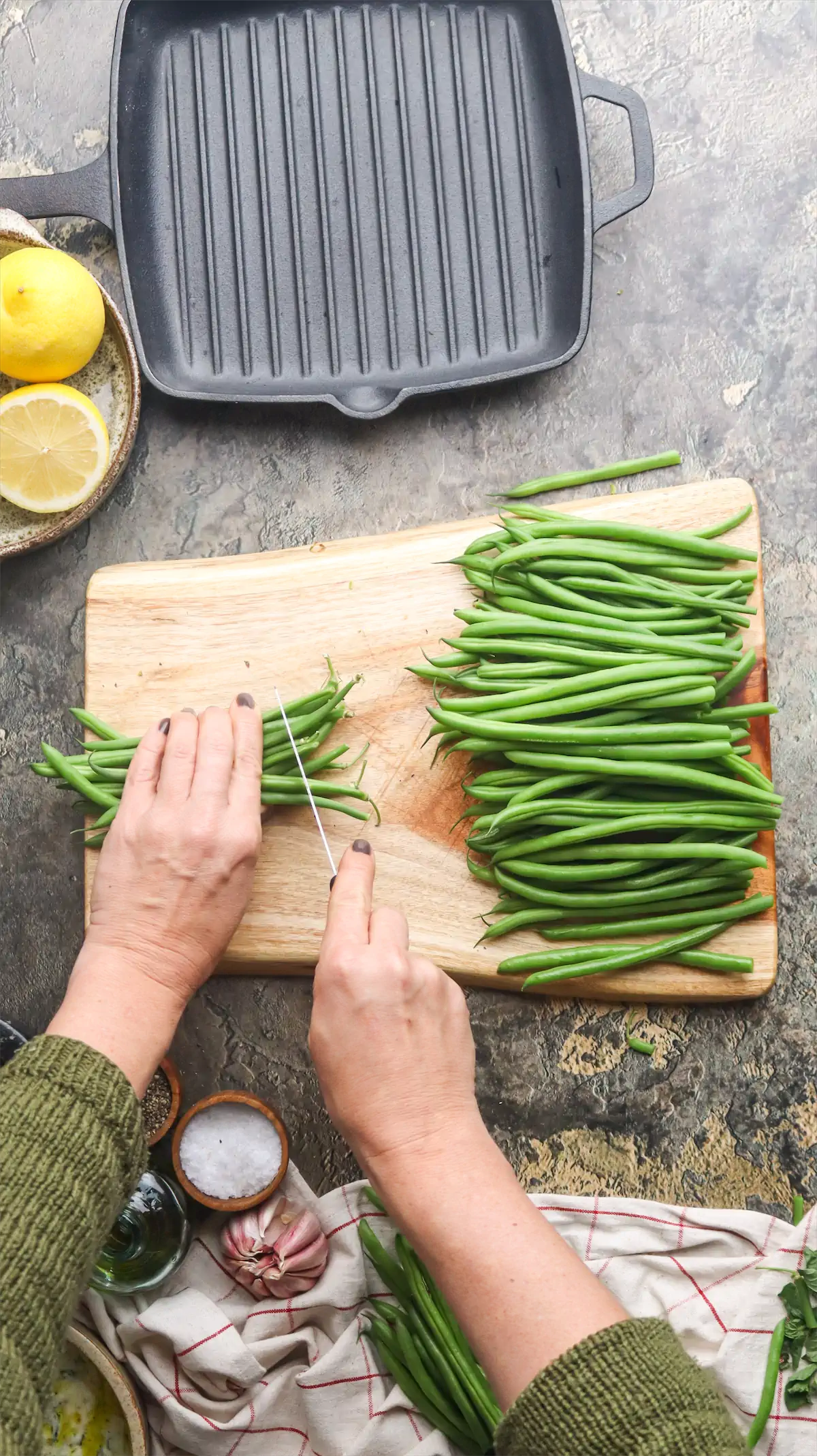 Green beans are being cut on the chopping board.