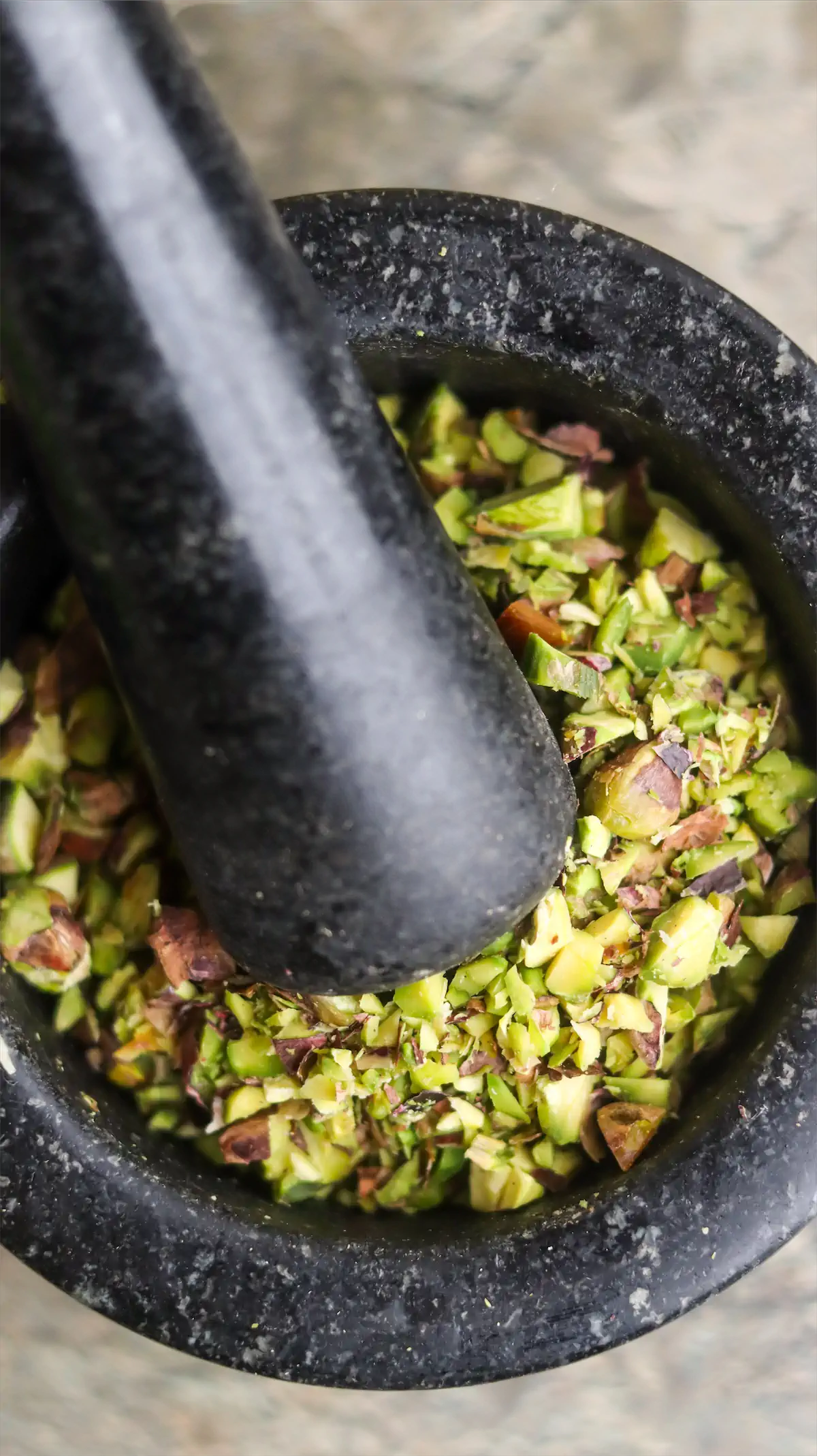 Pistachios are being crushed in a pestle and mortar.