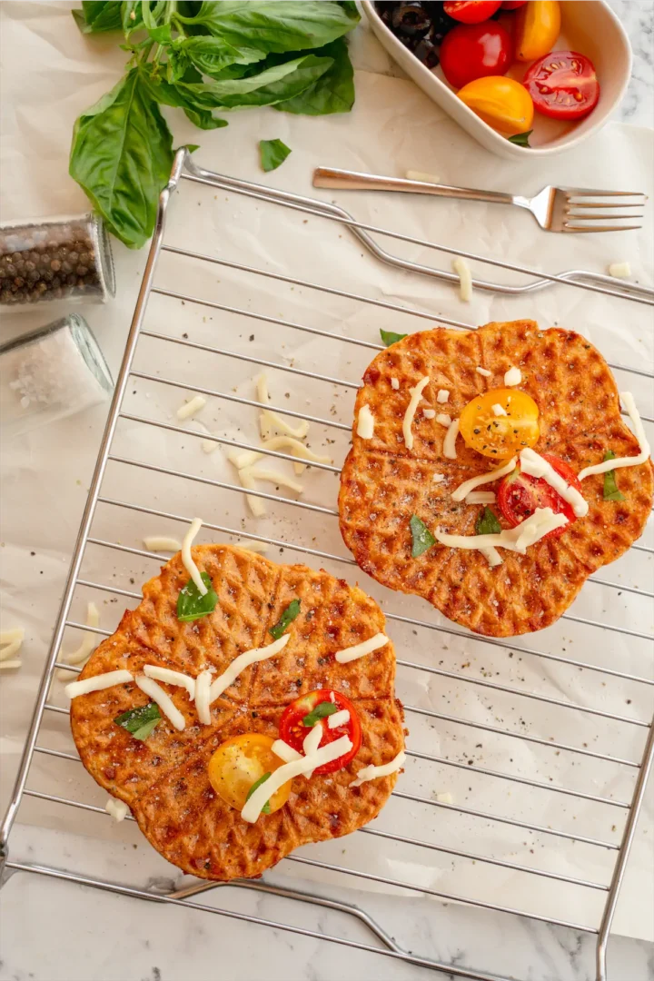 Keto chaffles topped with cheese and tomatoes.