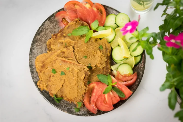 Keto steak recipe served on a plate with sliced tomatoes, cucumbers, and lemons.