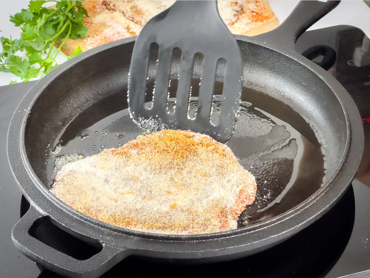 Steak getting cooked in a cast iron pan.