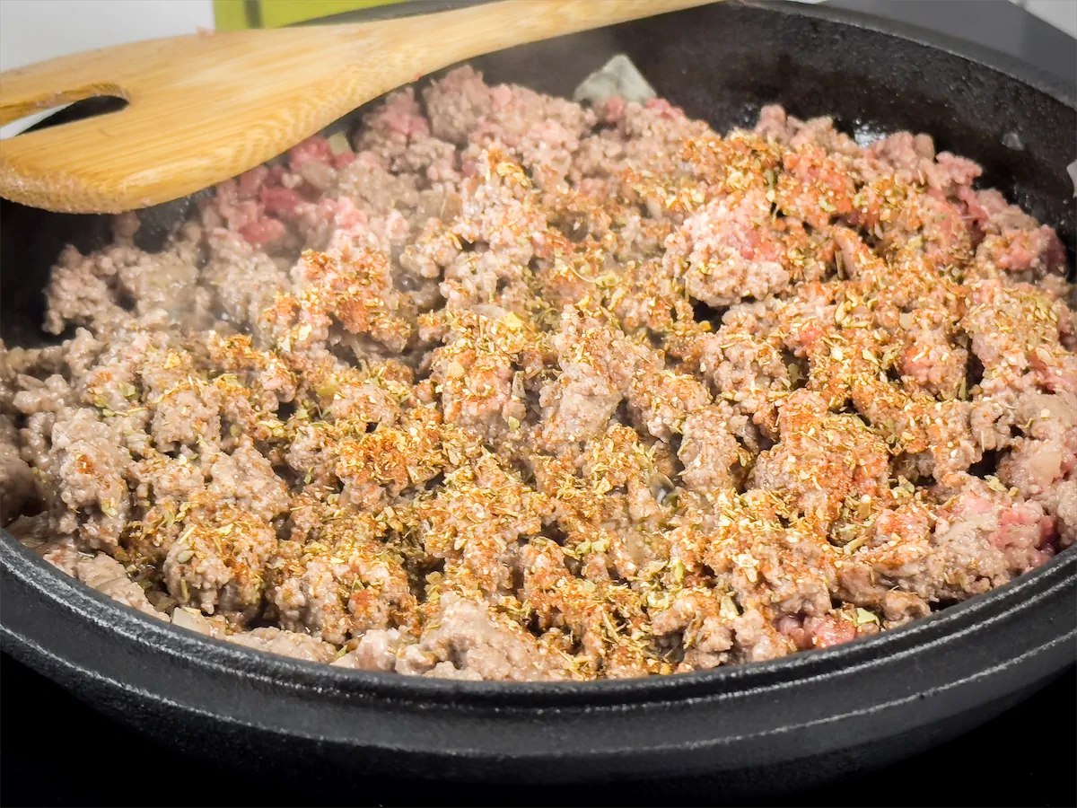 Taco seasoning added to ground pork in a skillet.