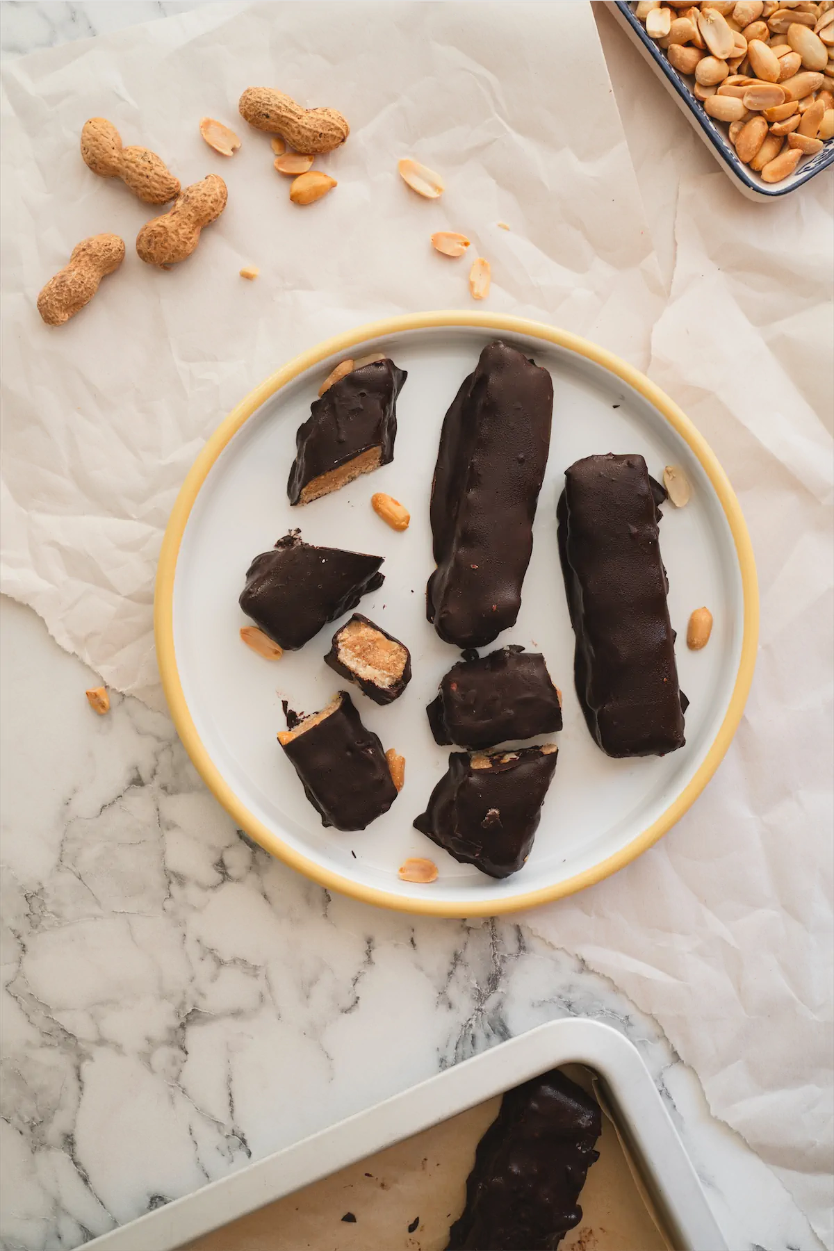 Keto copycat Snickers bar on a plate, and a few bars are cut to show the layers inside.