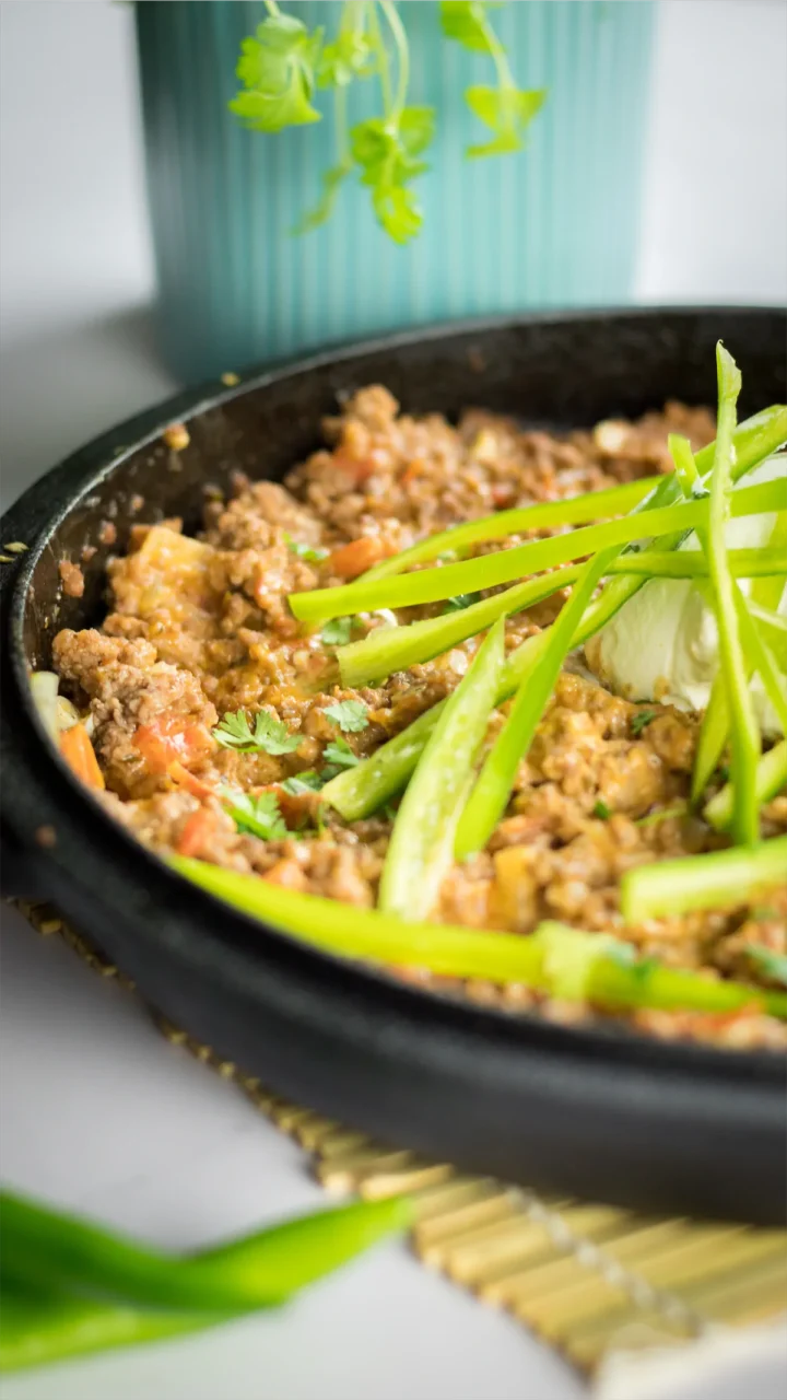 Keto taco casserole in a skillet, topped with sour cream, jalapeños, and fresh cilantro.