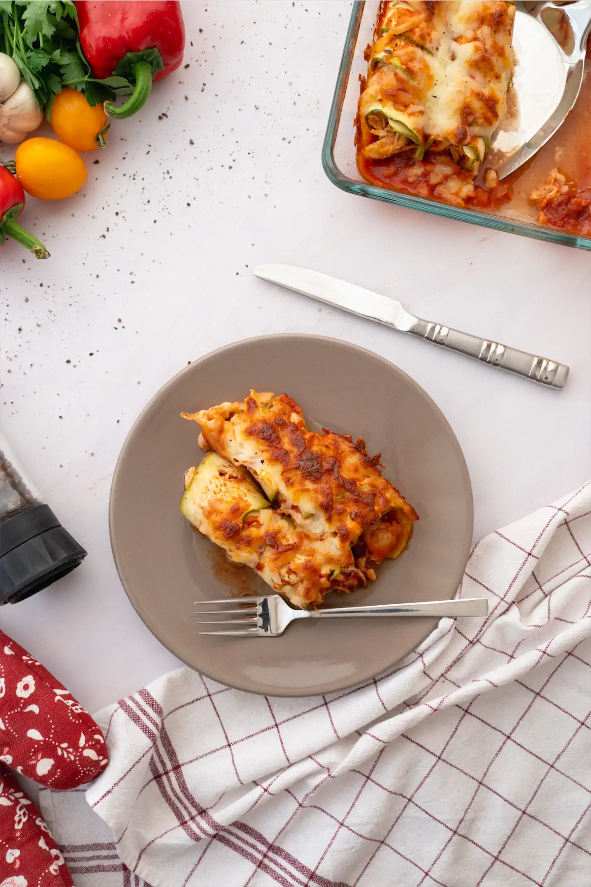 Cheesy zucchini enchiladas served on a plate with a fork and a spoon. 