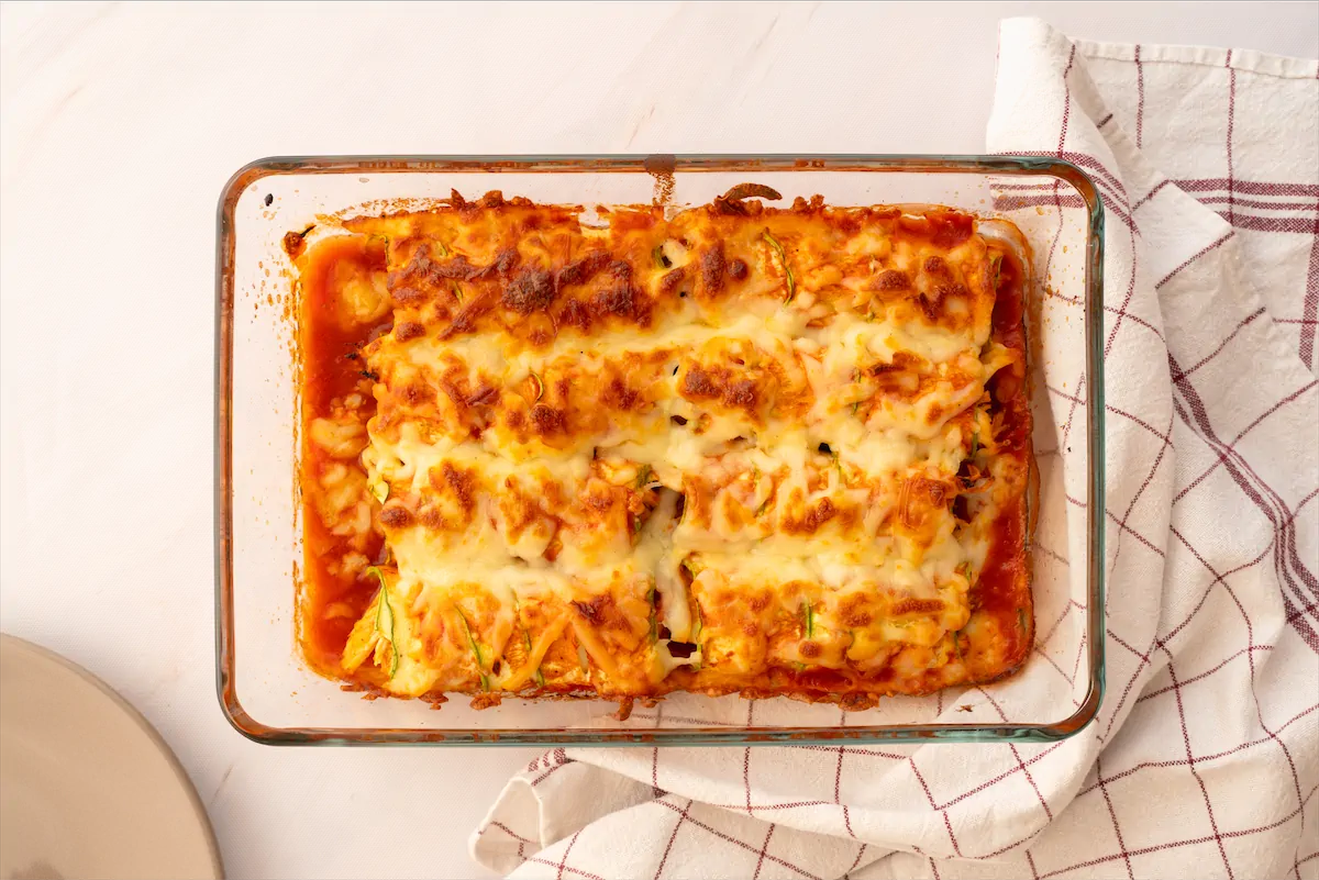 Baked cheesy zucchini enchiladas in a baking dish ready to be served.