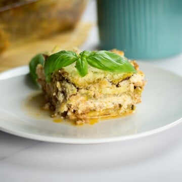 Keto zucchini lasagna garnished with fresh basil served on a plate.