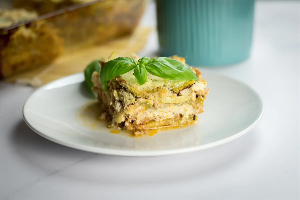 Zucchini lasagna, garnished with fresh herbs, served on a plate.