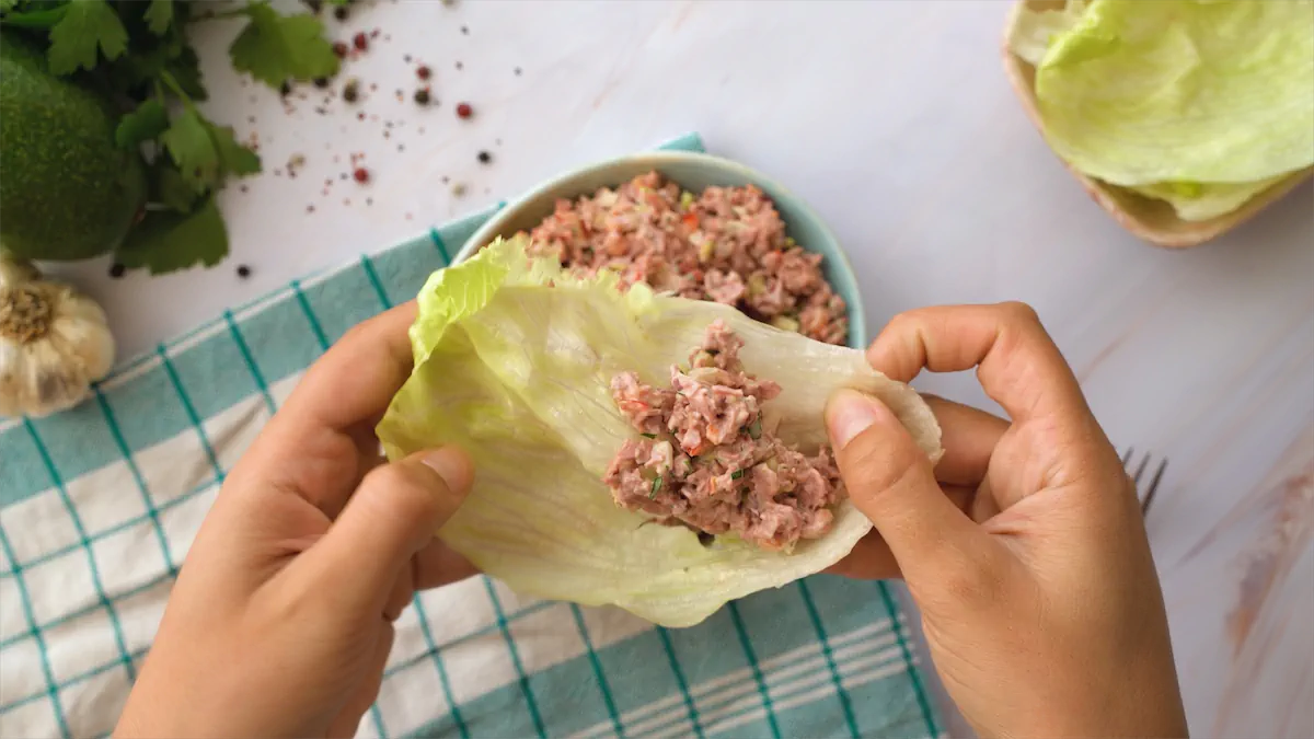 Two hands holding a serving of old-fashioned ham salad on a lettuce leaf.