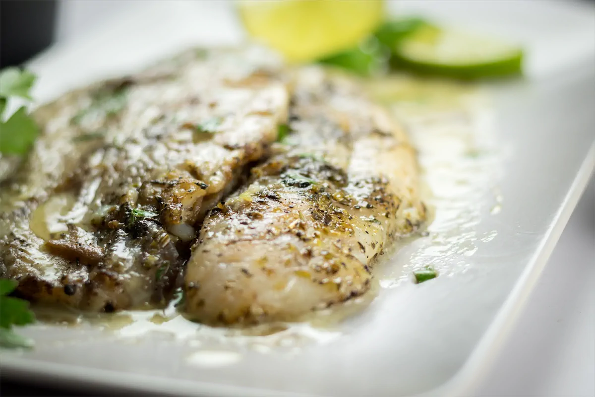 Low-carb pan-fried halibut filets with lemon butter sauce on a plate.
