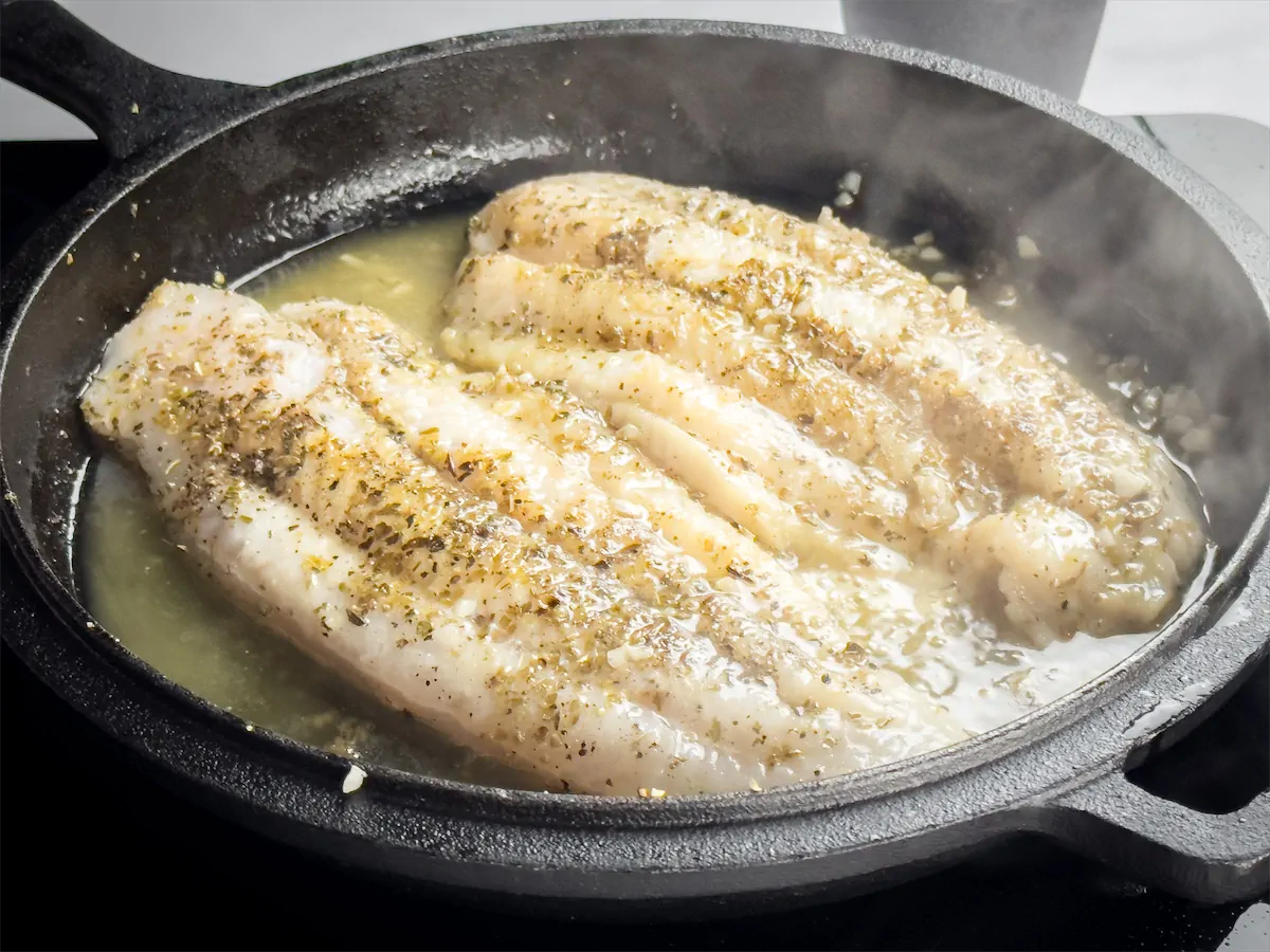 Pan-frying halibut fish in a cast iron skillet with garlicky olive oil and butter.
