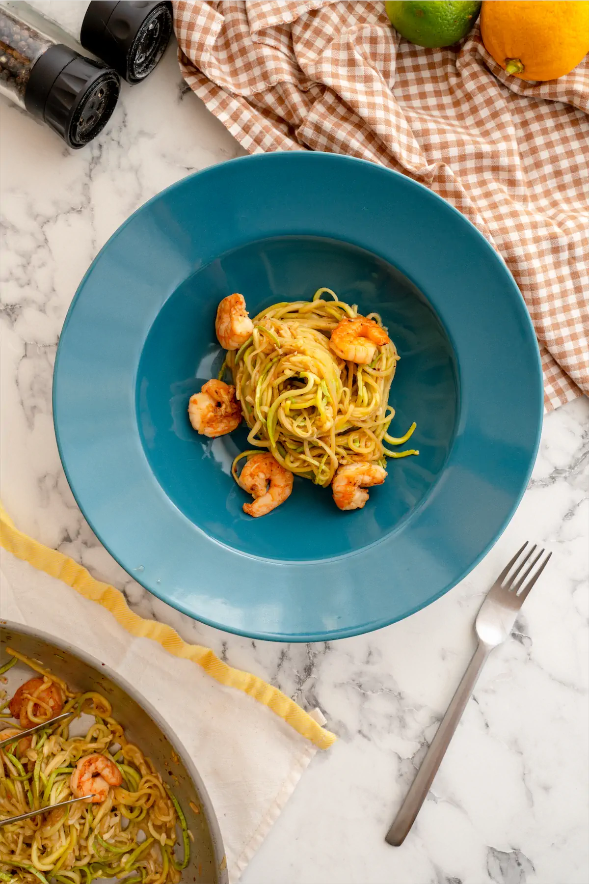 Homemade shrimp and zucchini noodles served on a plate and a fork.