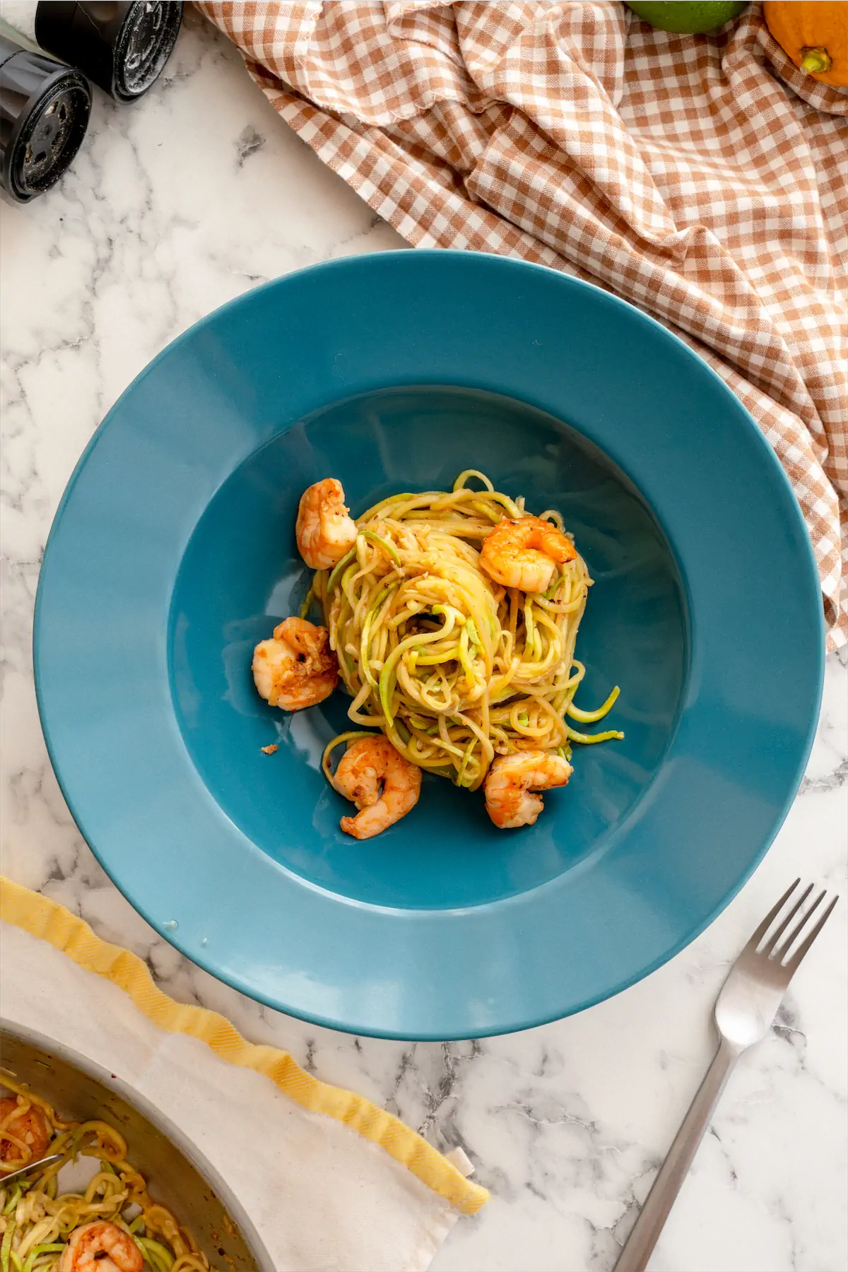 Low-carb zucchini noodles served on a pasta bowl and fork on a table.