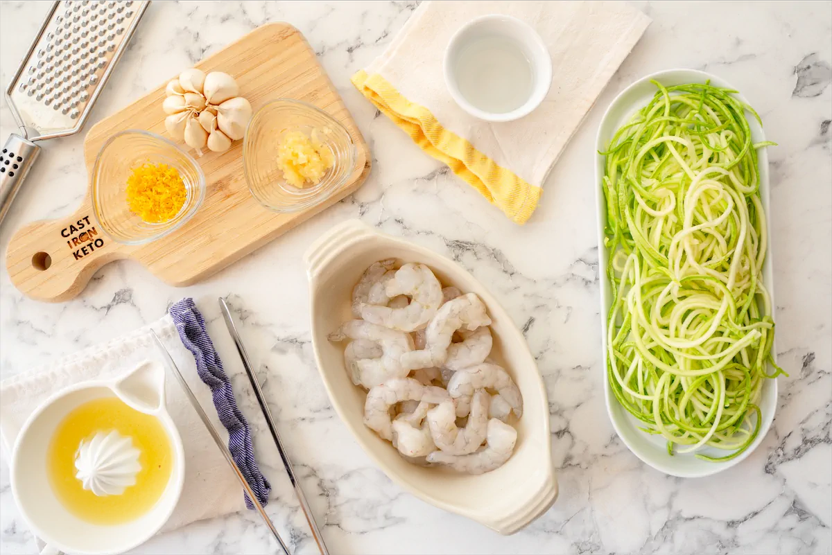 The ingredients including spiraled zucchini and shrimp gathered on the table to cook this zucchini noodles with shrimp.