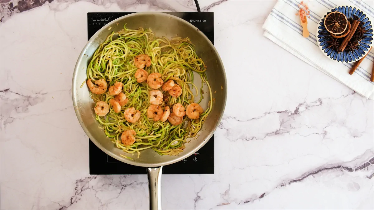 Cooking shrimp and zucchini noodles in the stainless steel skillet on an induction cooktop.