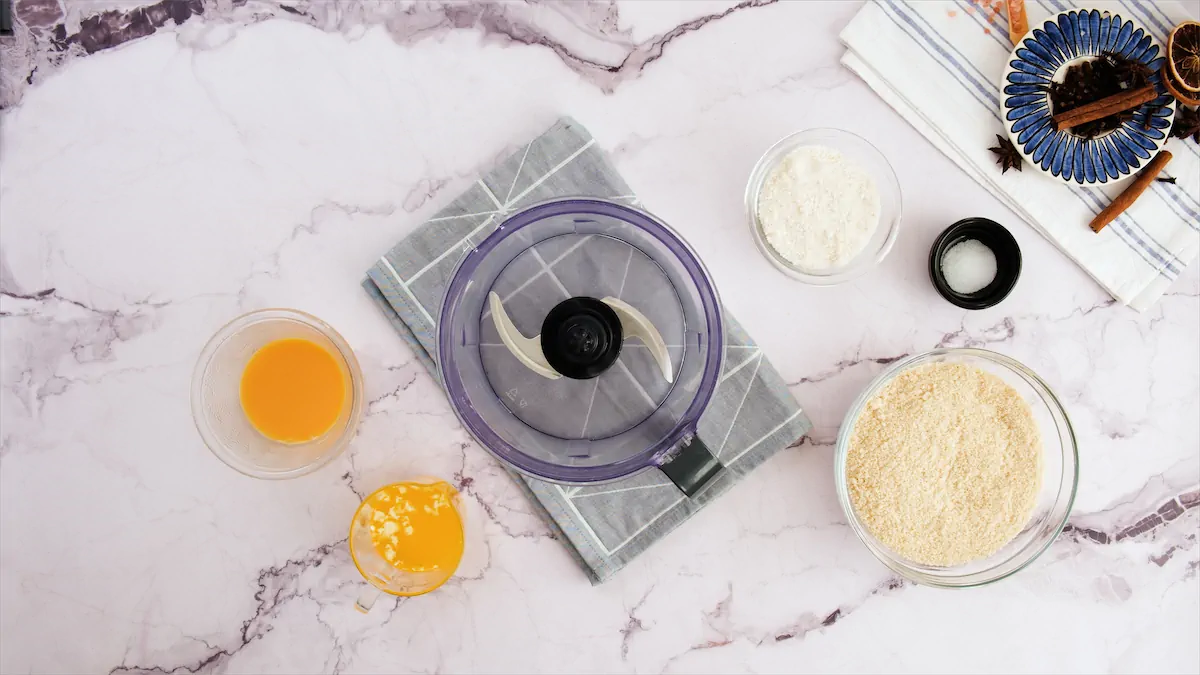 Food processor surrounded by the ingredients to prepare crust.