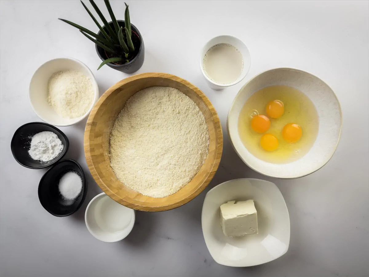 The required amount of almond flour, coconut flour, ground flaxseed, baking powder, salt, large eggs, unsalted butter, and unsweetened almond milk gathered and displayed on the table.
