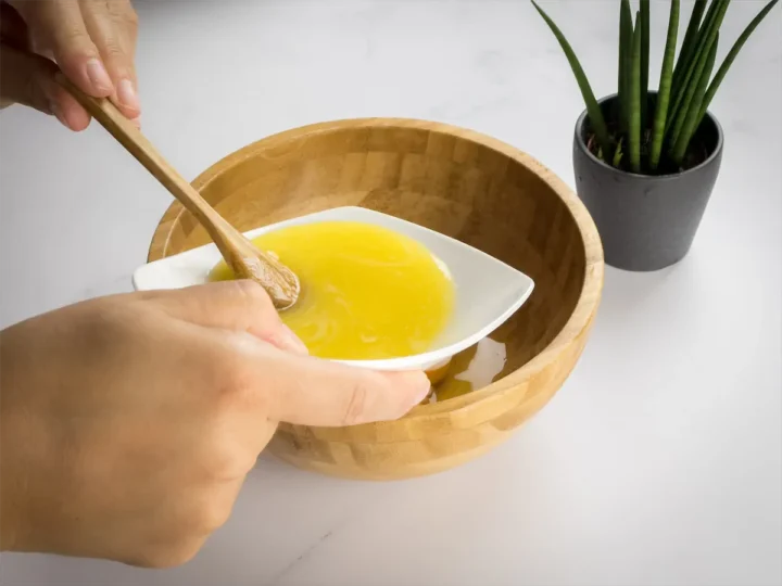Adding melted butter to a bowl containing eggs.