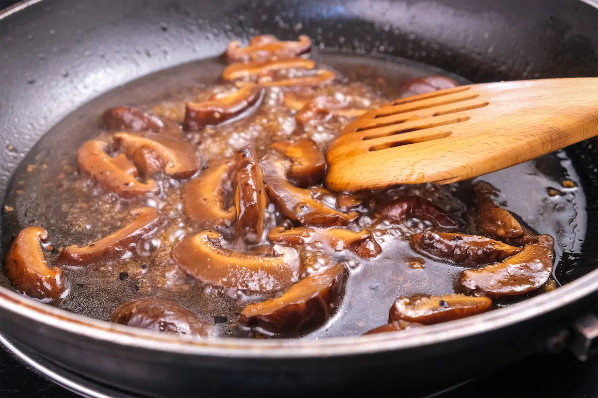 Adding the previously prepared sauce mixture to the pan where mushrooms were sautéed with ginger.