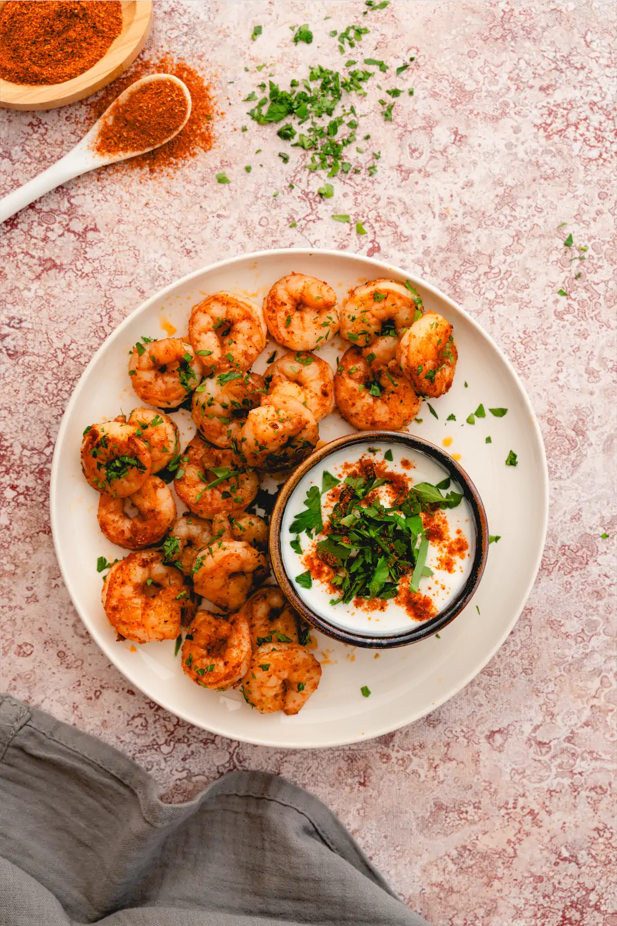 Keto Cajun shrimp on a white plate accompanied by a small bowl of dip.