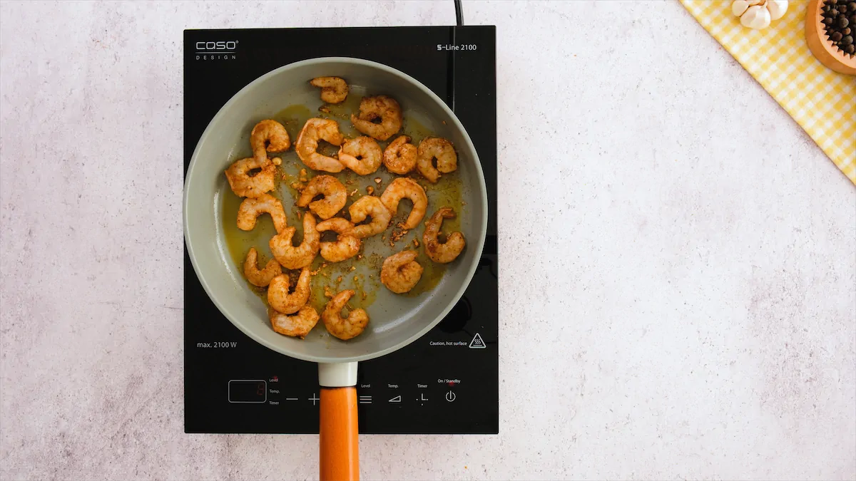 Cajun shrimp cooking in a pan on an induction stovetop.